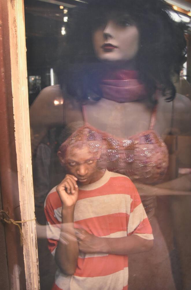 Ali Assmar, a 14-year-old mentally disabled child, watches mannequins in a dress shop, Baghdad