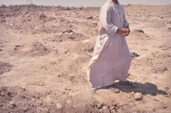 A relative of a slain Shia Muslim walks through a mass grave, Mahaweel