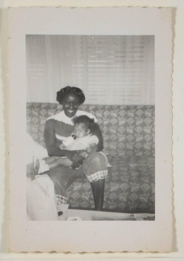 [Woman Holding Baby with Bottle on Sofa]