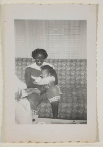 [Woman Holding Baby with Bottle on Sofa]