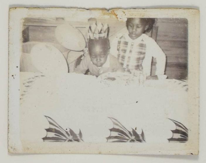 [Young Child in Birthday Hat Blowing out Candles, Young Girl Behind Them]
