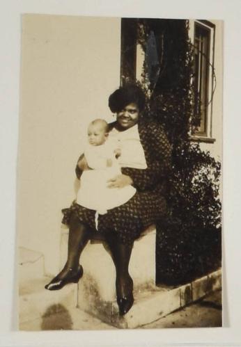 [Woman Smiling Holding Baby in Front of Porch]