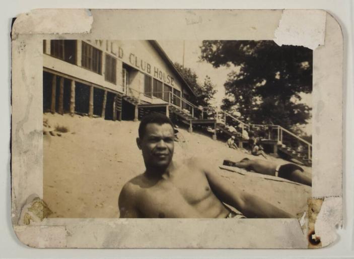[Man in Bathing Suit, Reclined on Sand in Front of Beach Club House]
