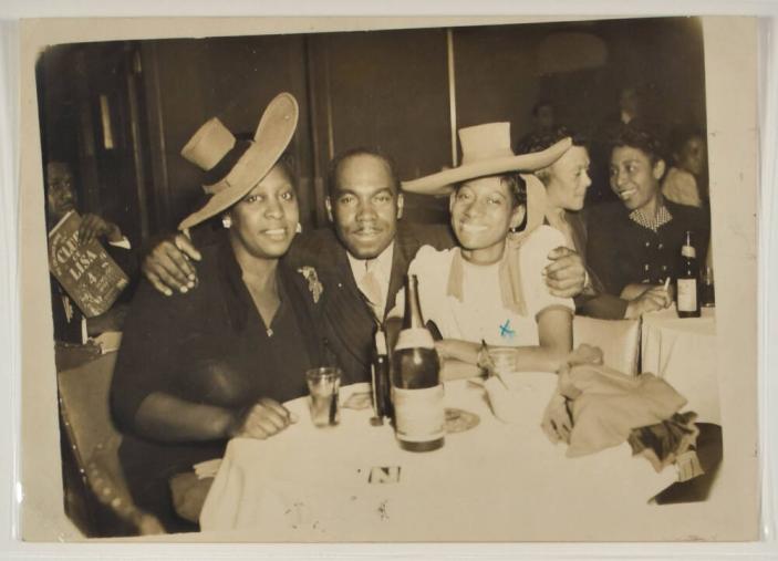 [Man with Arms Around Two Women at a Table at Club DeLisa]