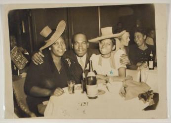 [Man with Arms Around Two Women at a Table at Club DeLisa]