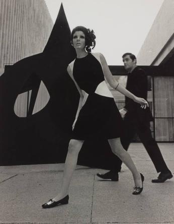[Female Model in Black and White Dress, Man and Sculpture in Background]