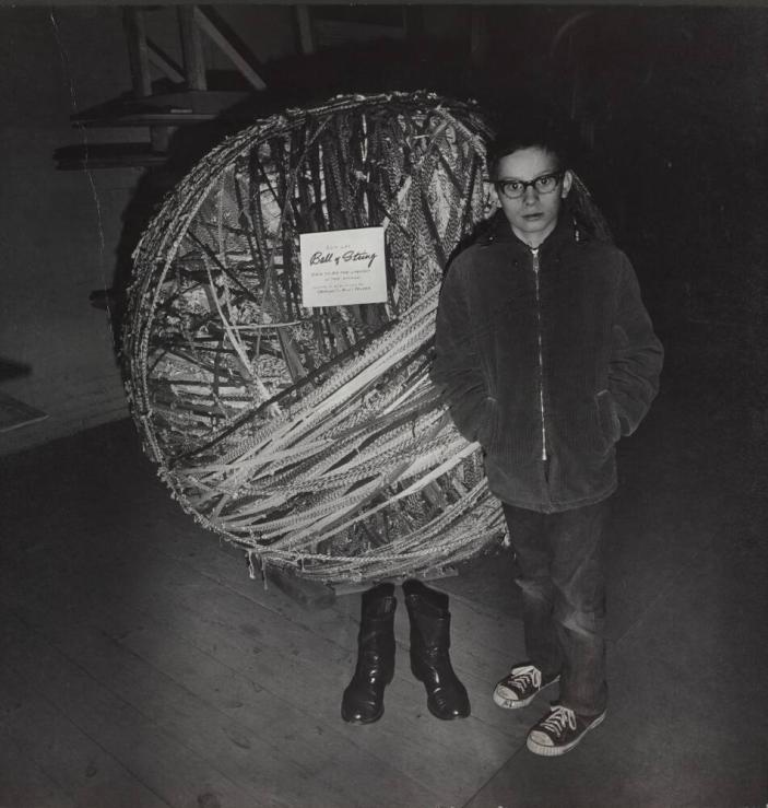 [Boy Standing in Front of “Ball of String” Pair of Legs]