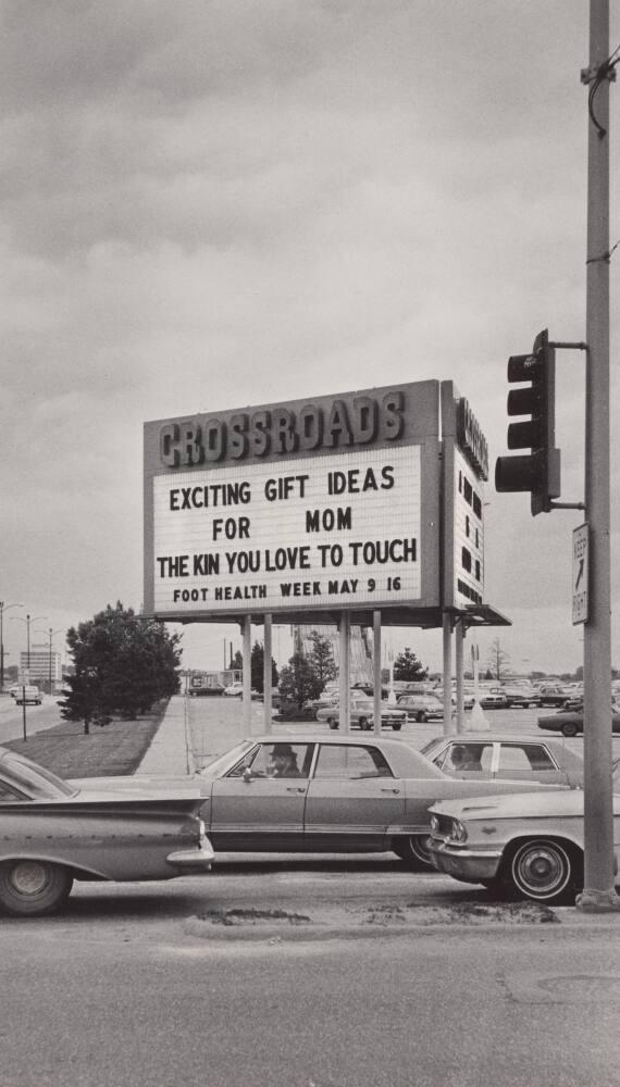 [Sign “Crossroads” “Exciting Gift Ideas for Mom…” Cars Traffic Light]