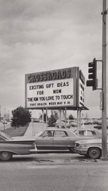 [Sign “Crossroads” “Exciting Gift Ideas for Mom…” Cars Traffic Light]