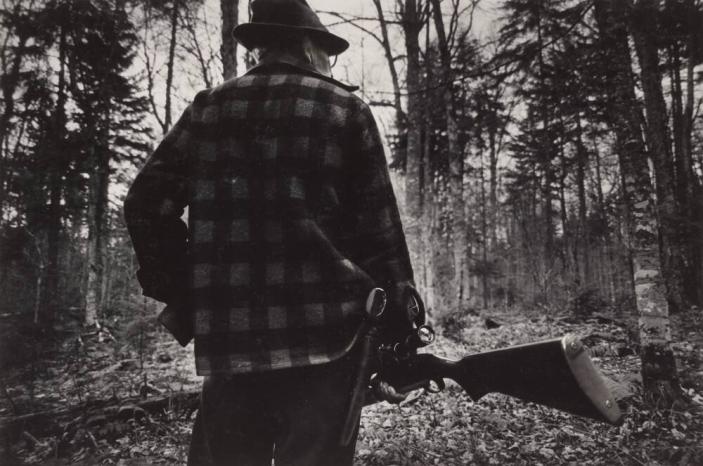 [Man in Plaid Shirt Holding Rifle, Pistol in Holster in the Woods]