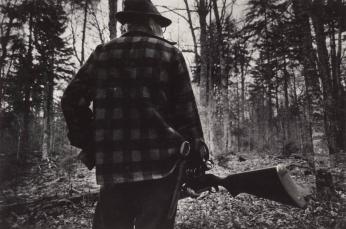 [Man in Plaid Shirt Holding Rifle, Pistol in Holster in the Woods]