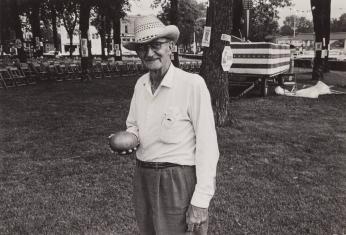 [Man in Straw Hat Holding Vegetable, Chairs, Field, Scott Orr Signs Back]