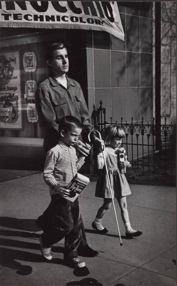 [Young Boy and Girl Carrying Popcorn Leading Blind Man With Cane on Street, Awning ‘Technicolor’]