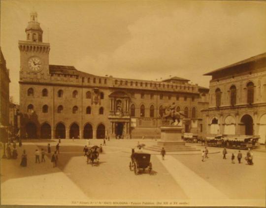 Open square w/ raised horse/rider sculpture, people strolling, horse-drawn carriages.