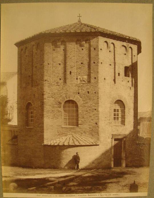 The octagonal Baptistry, cross on top.  Man standing against the wall.