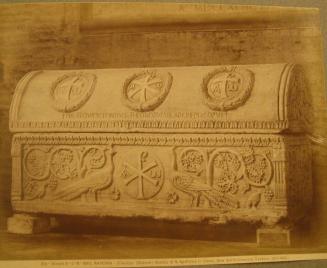 Tomb.  Domed top with three crosses encircled by laurel wreaths.  Base has carved peacock in front of tree/grape vine  on either side of central medallion.