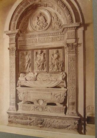 Arched monument.  Figure laid on top of coffin.   Three rectangular placques above. Circular placque within top curve of arch.