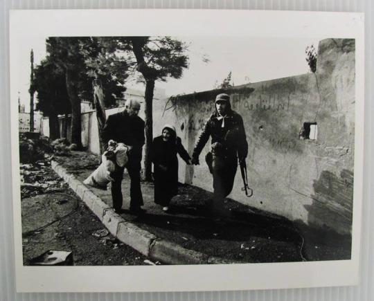 A Christian Phalangist soldier leads an old Armenian woman from her home in Quarantina