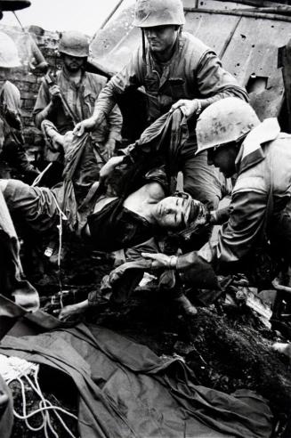 American soldiers dragging badly wounded North Vietnamese from foxhole